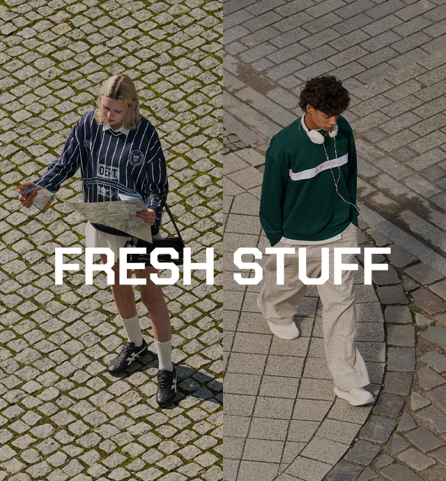 Baneris, reklamuojantis „FRESH STUFF” kolekciją – jauna moteris ir vyras vilki madingais miesto drabužiais su džemperiais, sportiniais bateliais ir aksesuarais, stovi ant grįstos gatvės, žiūri į žemėlapį ir klausosi muzikos. banner