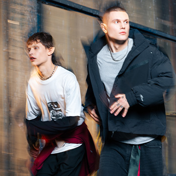 Το banner δείχνει δύο νεαρά άτομα που τρέχουν με χειμερινές αστικές ενδυμασίες — το ένα με ανοιχτόχρωμο T-shirt και σκουρόχρωμο μπουφάν ριγμένο στο χέρι και το άλλο με μαύρο φουσκωτό μπουφάν και γκρι T-shirt. banner