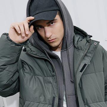 Mees rohelises sulejopes, hallis kapuutsiga dressis ja musta nokkmütsiga, poseerib streetwear stiilis. banner